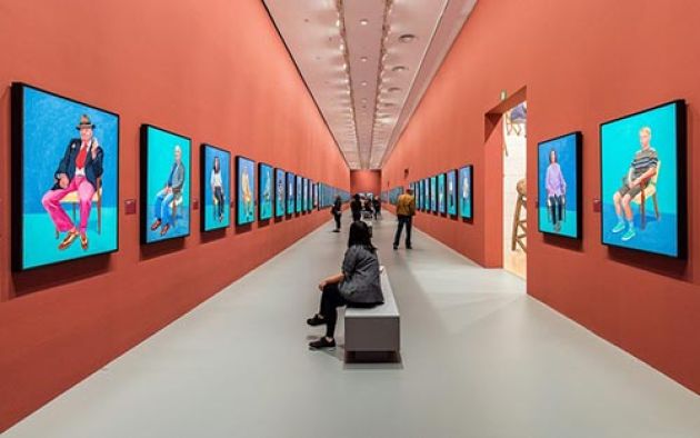 Woman looking at a row of paintings hanging on the wall of an art gallery